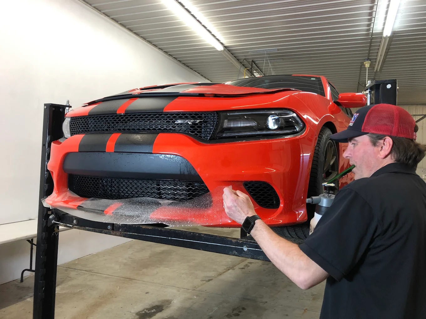 Paint protection film being installed on a red performance car
